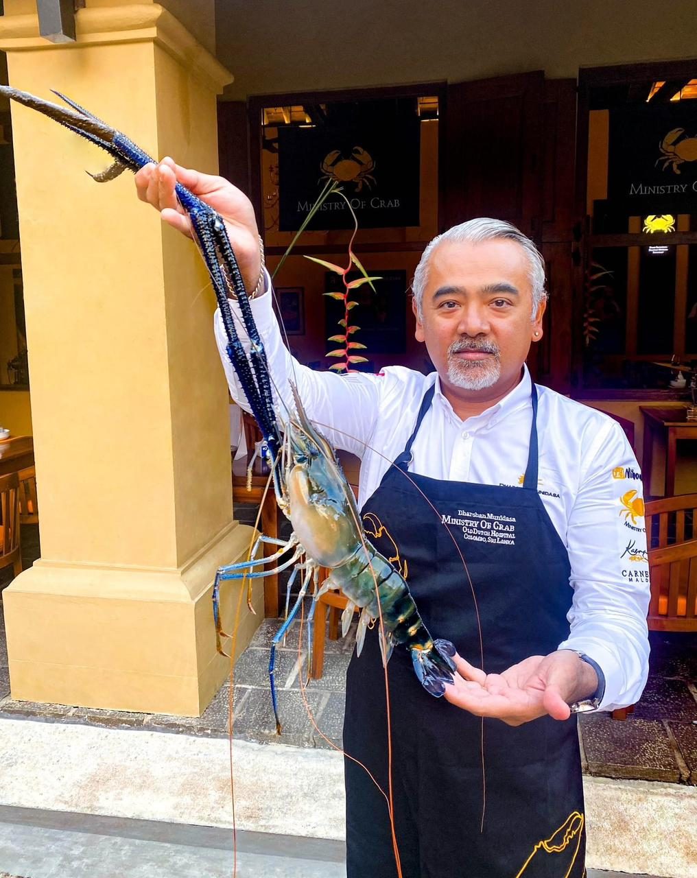 Chef Dharshan Munidasa holding a giant freshwater prawn by its claws at the entrance to Ministry of Crab