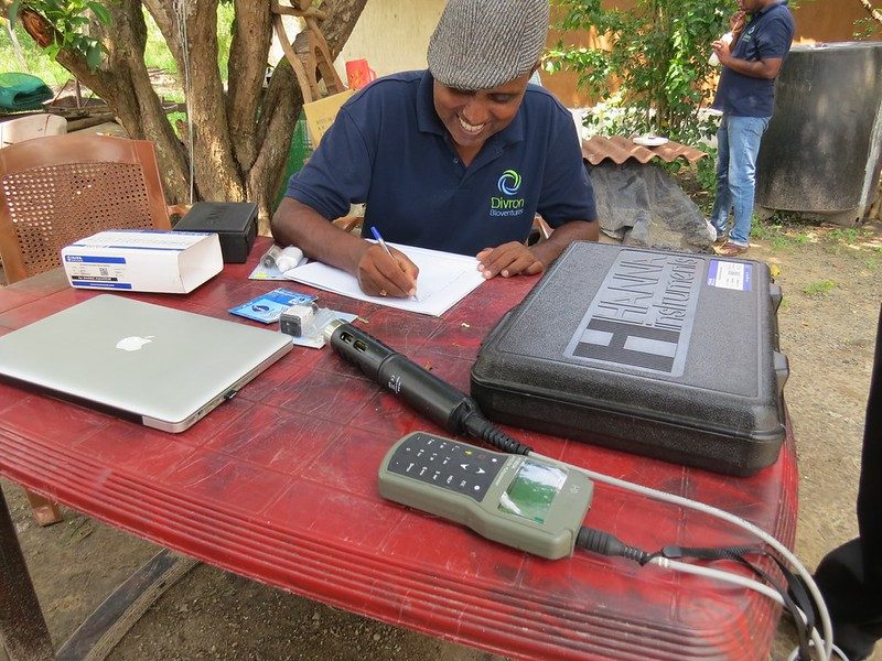 Divron staff recording water-quality instrument readings in the field